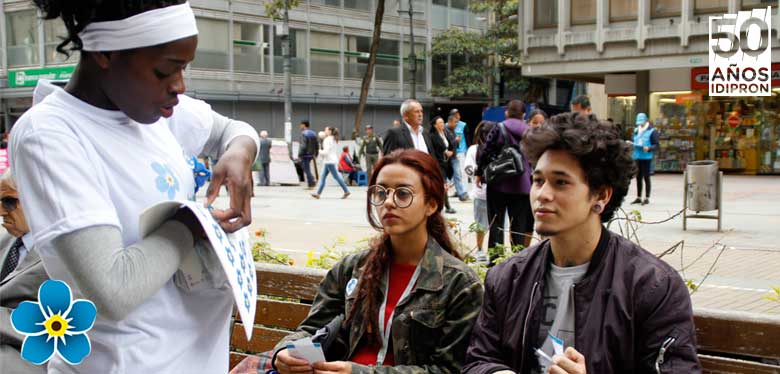 Jóvenes IDIPRON entregando flor no me olvides